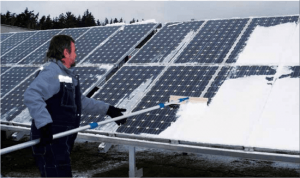 Mann entfernt Schnee von Photovoltaik Modulen