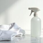 Fleckenwasser – Sprühflasche mit Fleckenentferner neben weißem Hemd